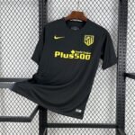 Camiseta visitante Atlético de Madrid 2016-17 en color negro con detalles en azul marino y amarillo, escudo bordado y patrocinio Plus500