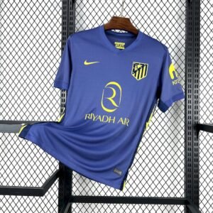 Camiseta visitante Atlético de Madrid 2025‑26 en azul marino con detalles en amarillo vibrante y paneles laterales inspirados en rayos
