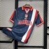 Camiseta visitante Atlético de Madrid 1998-99 en azul marino con franja roja y blanca, escudo bordado y patrocinio Marbella