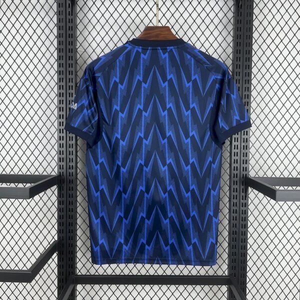 Camiseta visitante Arsenal 25/26 azul marino con rayos azul real, detalles rojos y logos en plata metálica