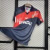 Camiseta visitante Atlético de Madrid 1996-97 en azul marino con franja diagonal roja y blanca, escudo bordado y patrocinio Bandai